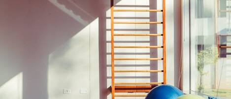 A room with a wooden ladder, exercise balls, and a yoga mat.
