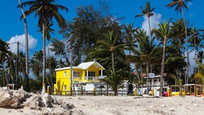 A yellow building with a balcony, surrounded by palm trees and a clear blue sky. - Corales Colonial II With Private Beach,los Corales (Punta Cana)