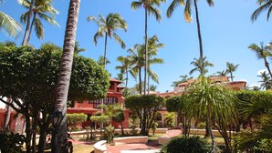A resort with palm trees, a red building, and a clear blue sky. - Corales Colonial II With Private Beach,los Corales (Punta Cana)