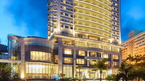 A high-rise hotel with multiple floors, large windows, and a well-lit entrance area. - Wyndham Legend Halong Hotel (Bai Chay)