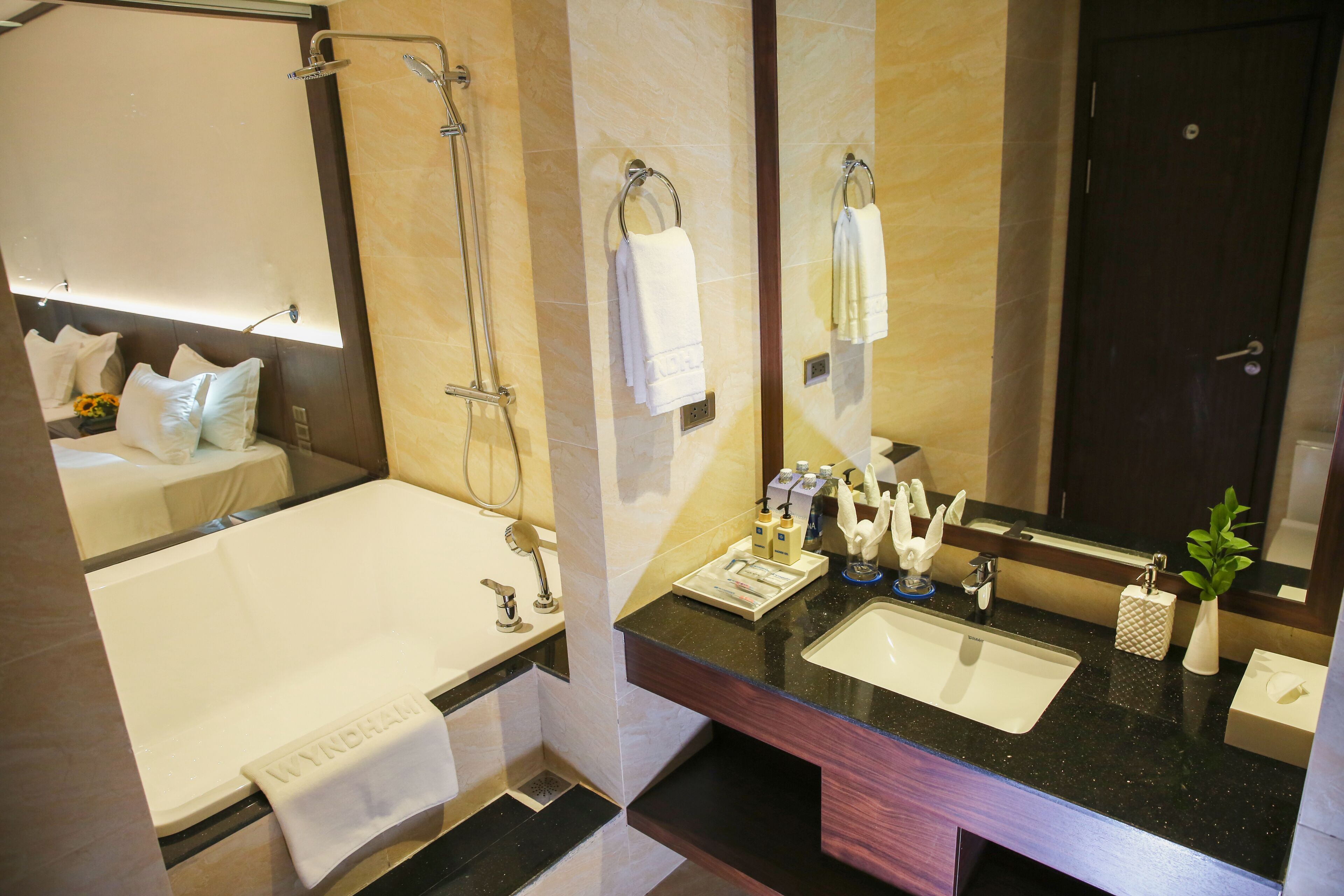 A modern bathroom with a bathtub, two sinks, a large mirror, and a shower.