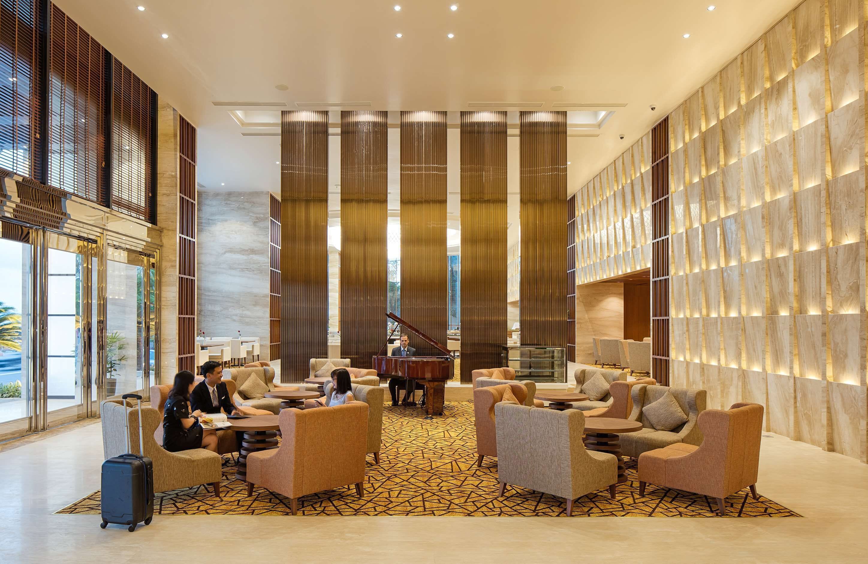 Um lobby espaçoso com um piano de cauda, assentos confortáveis e uma grande janela com vista para o exterior.