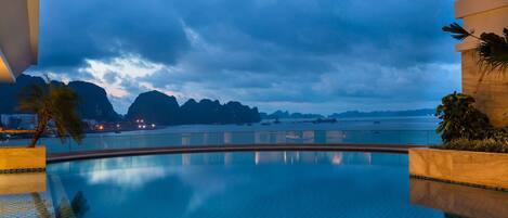 A pool with a view of the sea and mountains.