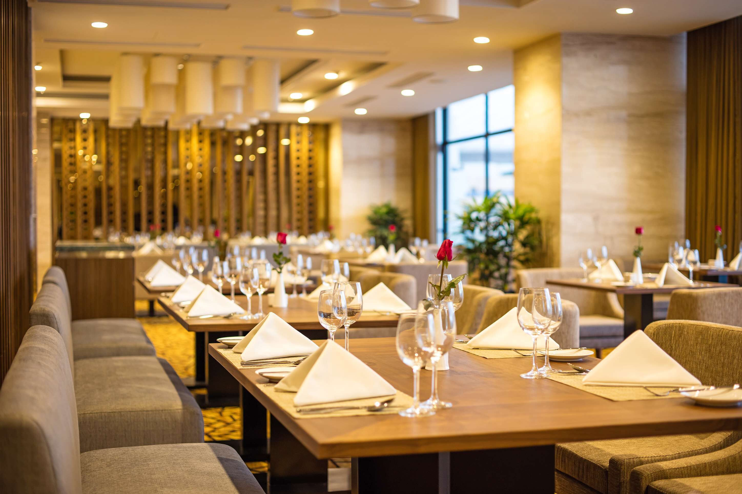 A restaurant with long tables set with white napkins, wine glasses, and cutlery.