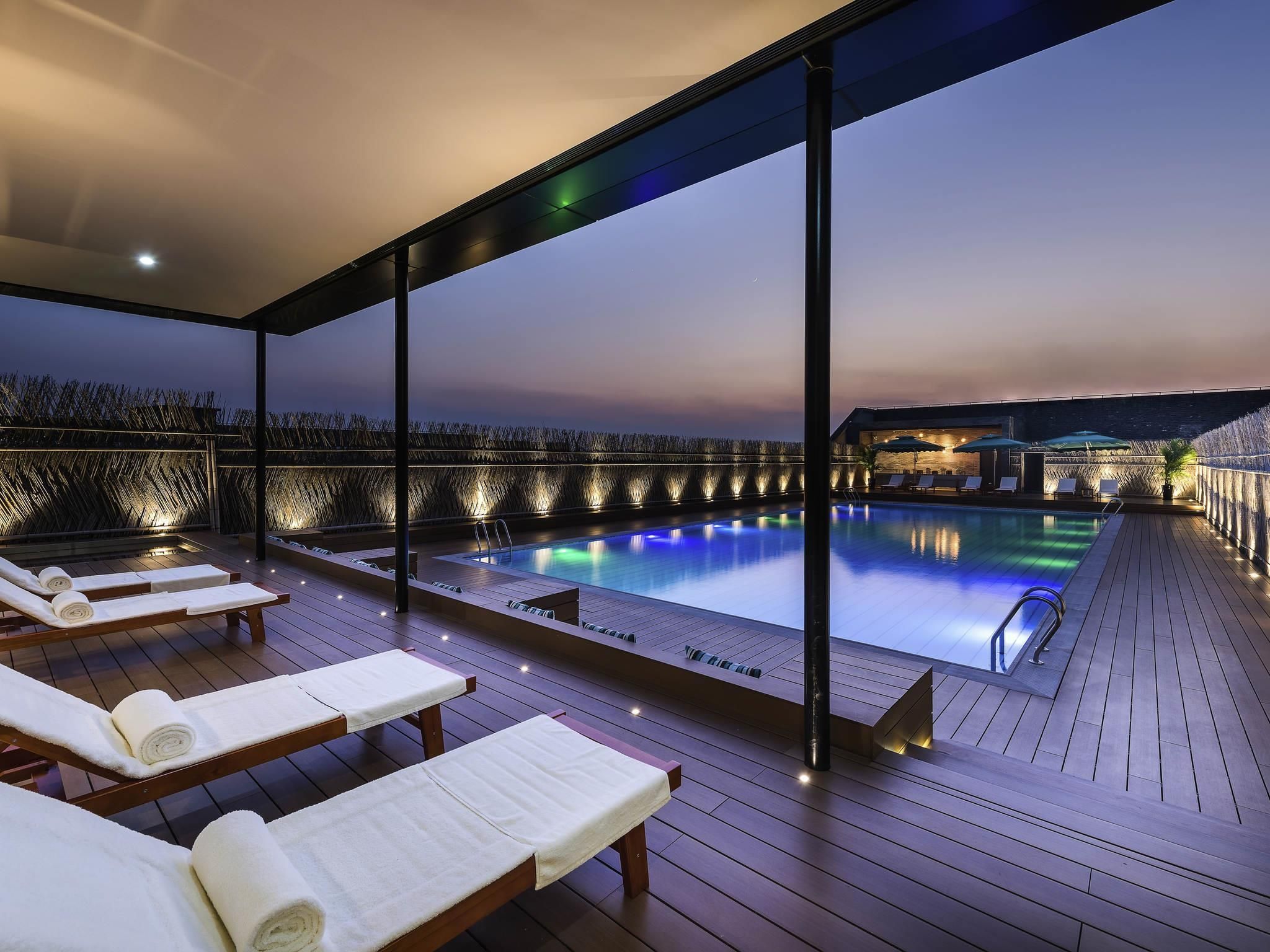 A rooftop pool area with lounge chairs and a view of the ocean.