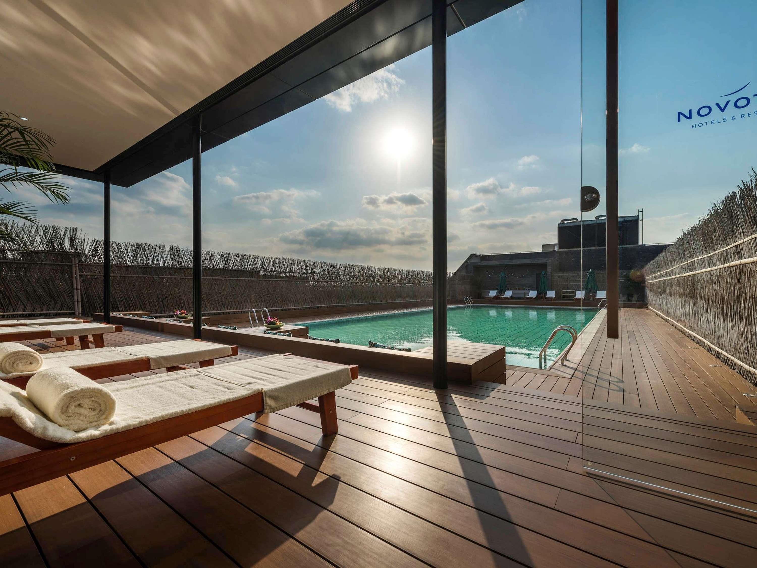A rooftop pool area with sun loungers and a view of the city skyline.