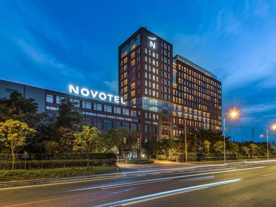 Et hotel med et tydeligt 'NOVOTEL' skilt, moderne arkitektur og en godt oplyst facade.