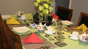 Une table à manger dressée avec plusieurs théières, des tasses et un centre de table composé de fleurs jaunes.