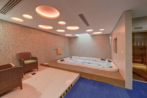 Un cuarto de spa con un jacuzzi, dos sillones de mimbre y una camilla de masaje.
