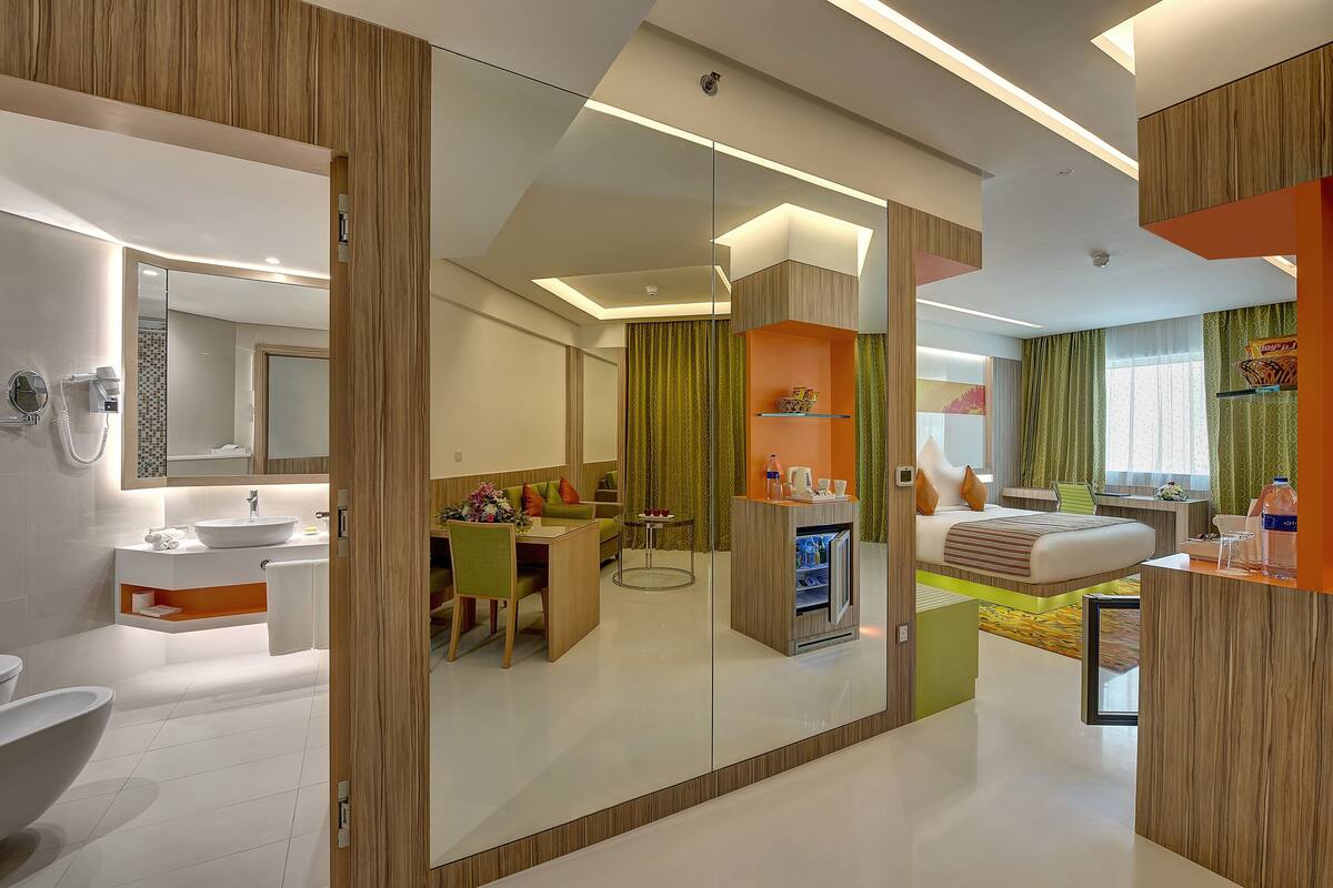 A modern hotel room with a bathroom, a dining area, and a bedroom.