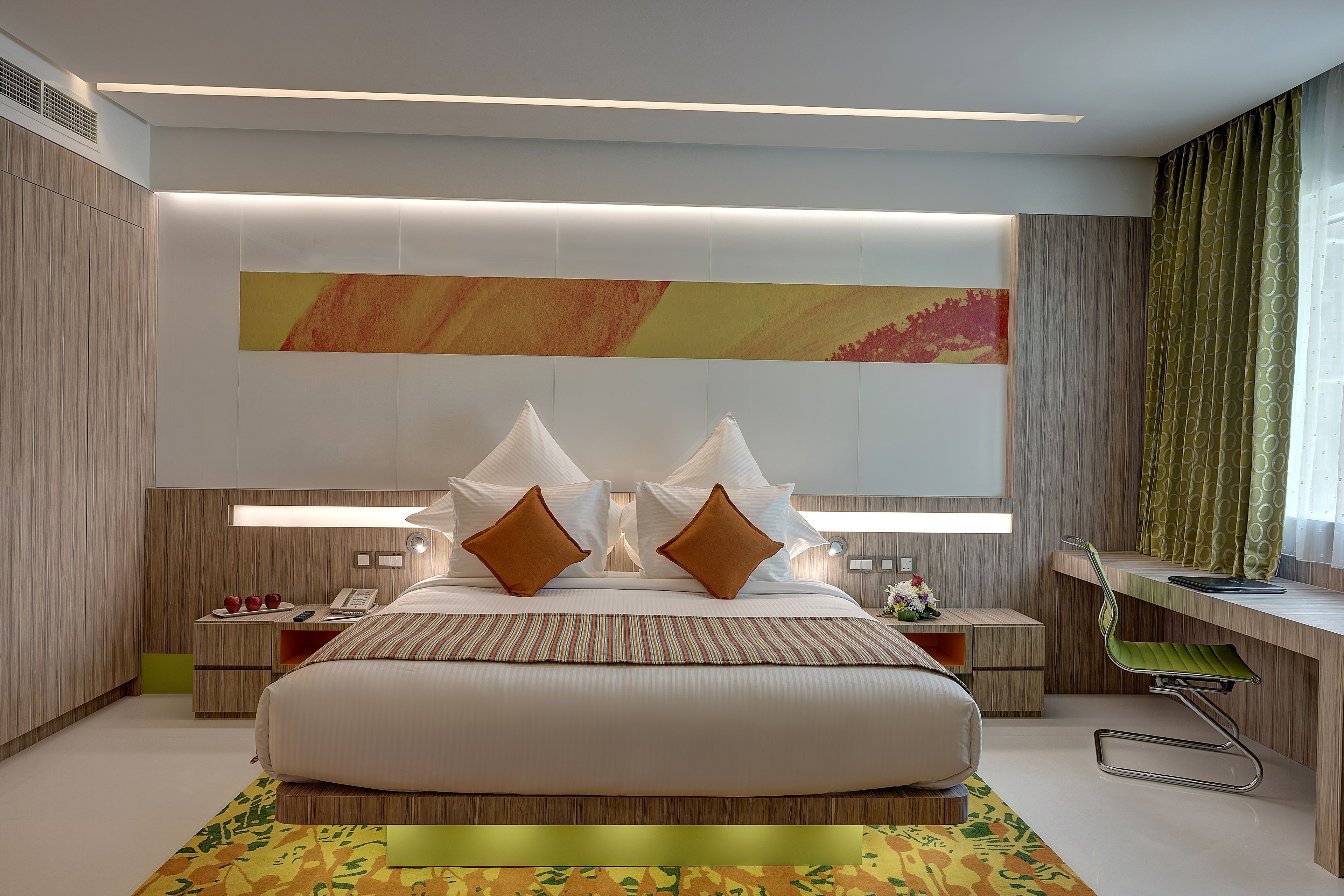 A modern hotel room with a large bed, bedside tables, a desk, and a chair.