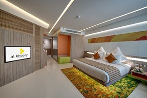 A modern hotel room with a large bed, a TV, and a logo on the wall.