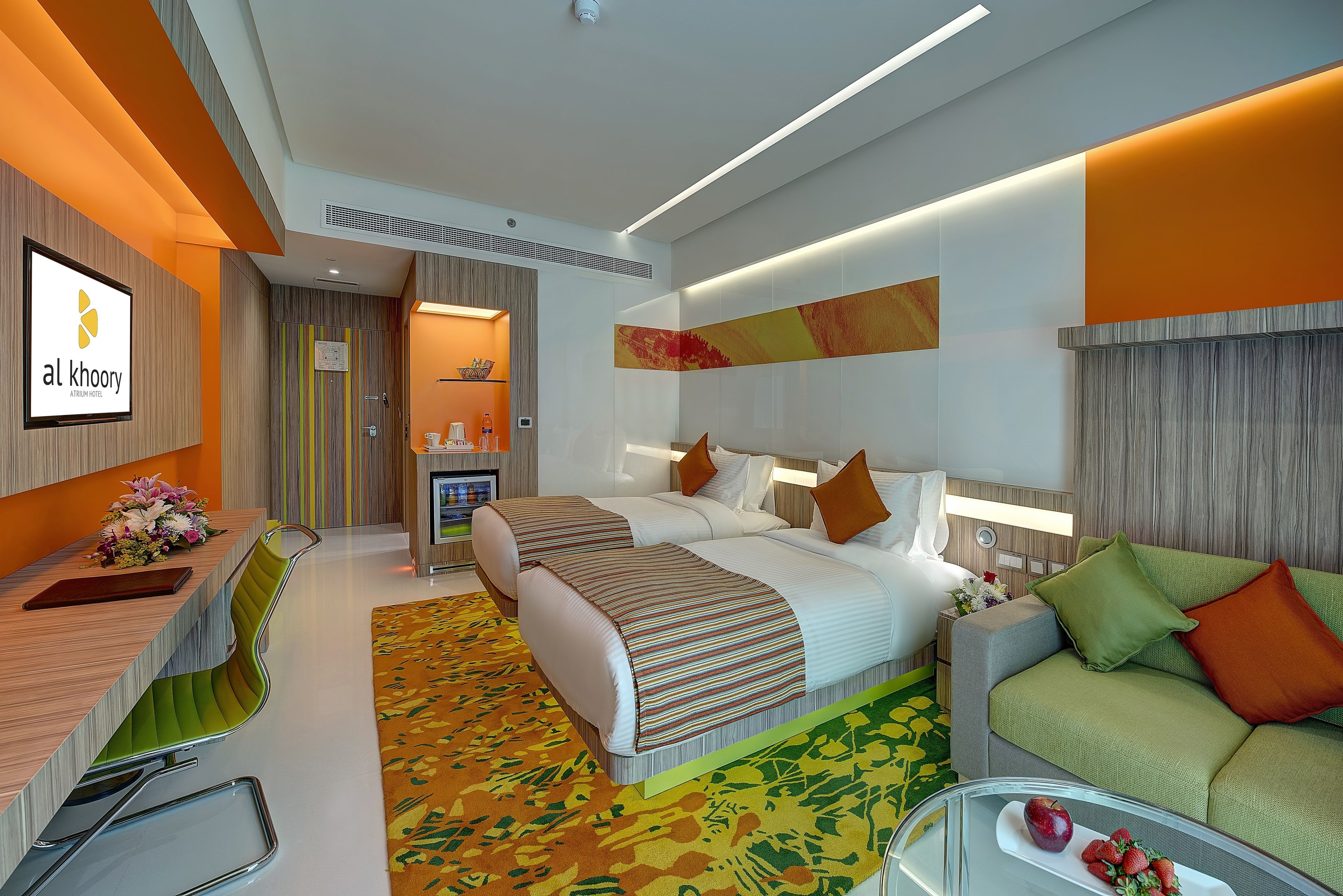 A modern hotel room with a bed, a sofa, a desk, and a TV.