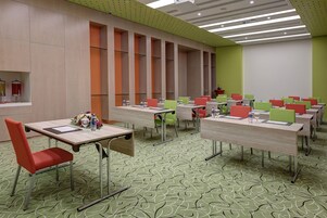 A conference room with multiple tables and chairs, equipped with water bottles and notepads.
