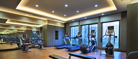 Un gimnasio moderno con equipo de ejercicio, ventanas amplias y suelo de madera.