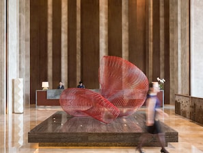 A lobby with a reception desk, a large red abstract sculpture, and a marble pillar. - Pullman Nanchang Sunac (Nanchang)