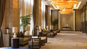 A hotel lobby with a long reception desk, multiple seating areas, and a large chandelier. - Pullman Nanchang Sunac (Nanchang)