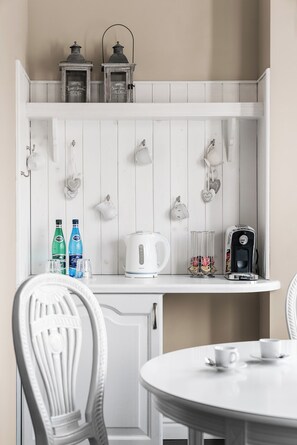 Un buffet en bois blanc, orné de deux lanternes, d’une bouilloire et d’une machine à café.