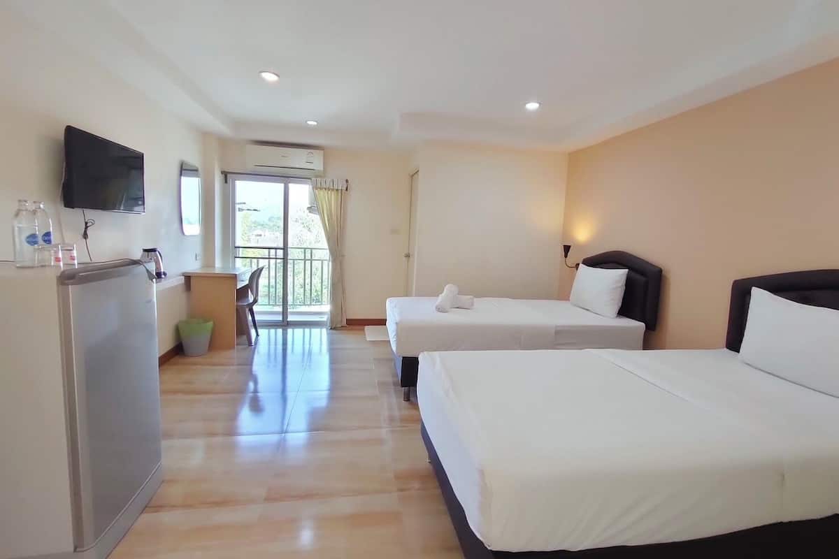 Ein Hotelzimmer mit zwei Betten, einem Schreibtisch, einem Fernseher und einem Balkon mit Blick.
