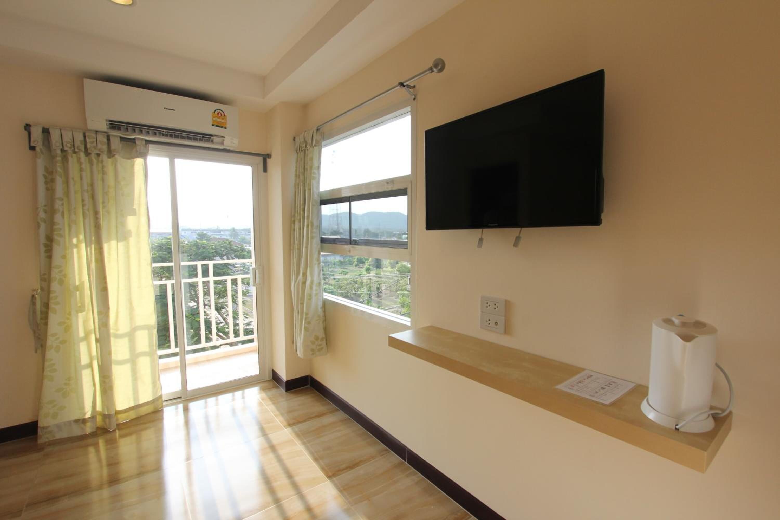 A room with a large window, a mounted TV, and a ceiling fan.