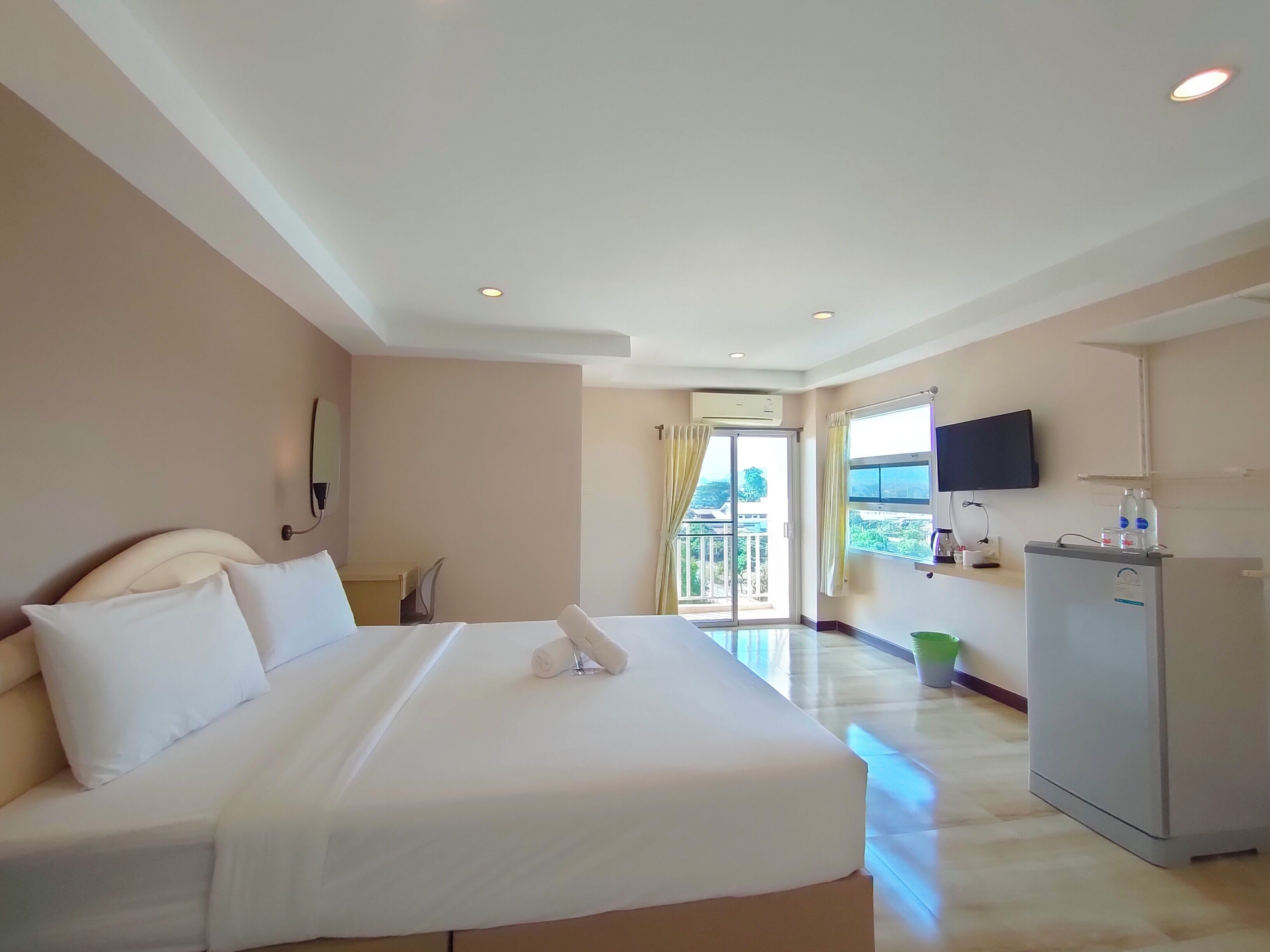 Habitación de hotel con una cama grande, un escritorio, un televisor de pantalla plana y un refrigerador.
