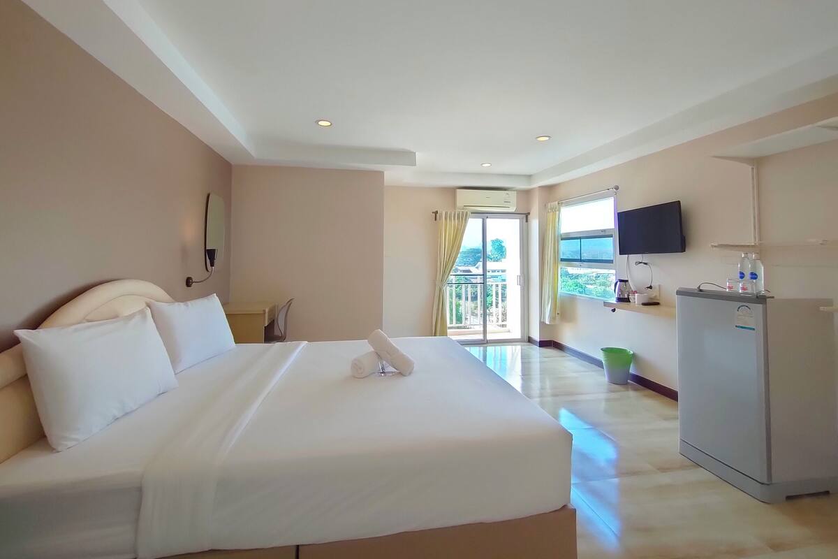 Habitación de hotel con una cama grande, un escritorio, un televisor de pantalla plana y un refrigerador.