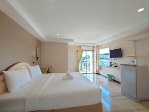 Habitación de hotel con una cama grande, un escritorio, un televisor de pantalla plana y un refrigerador.