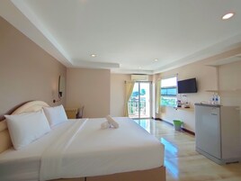 Habitación de hotel con una cama grande, un escritorio, un televisor de pantalla plana y un refrigerador.