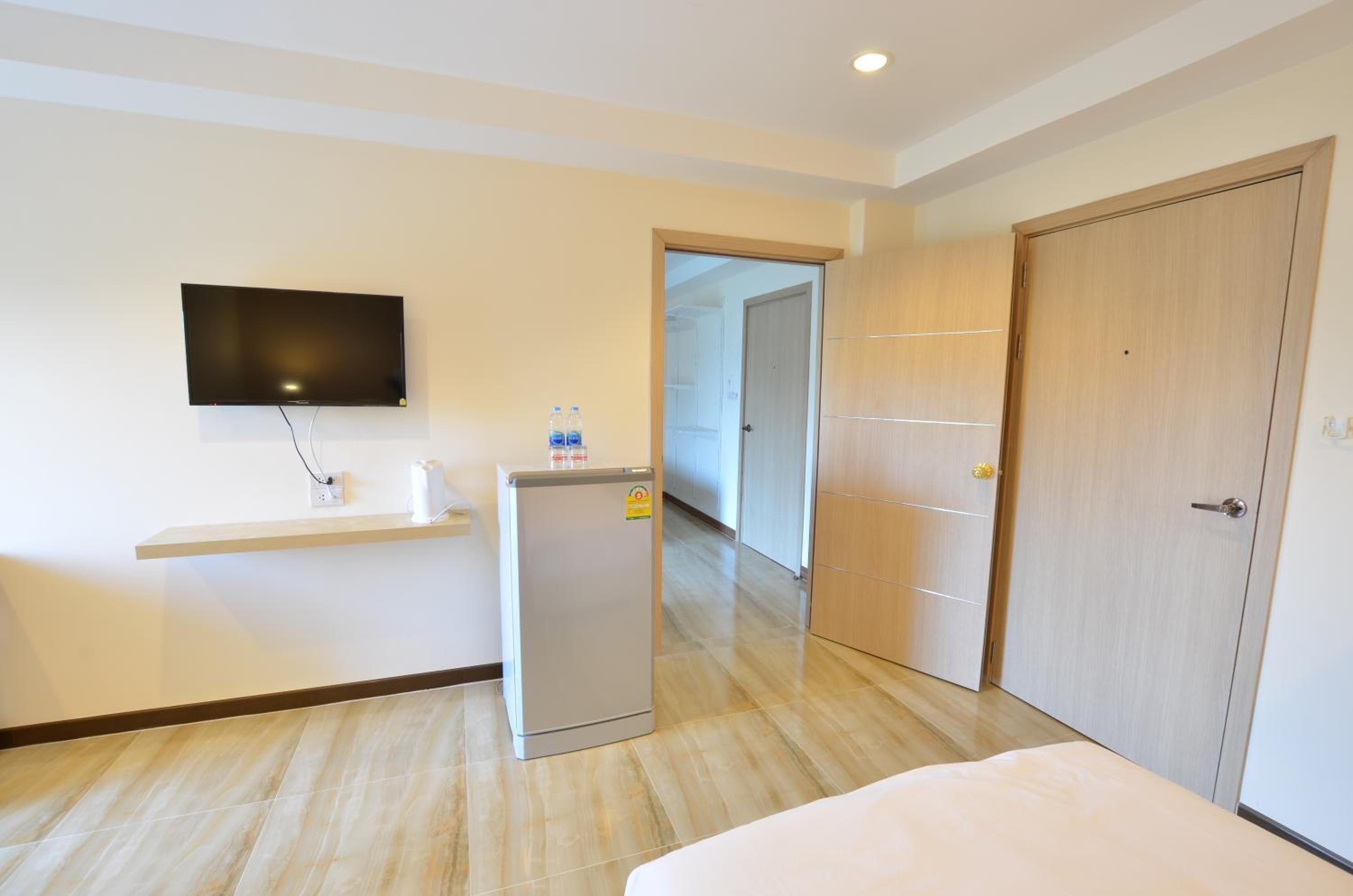 Hotelkamer met een bed, een aan de muur bevestigde televisie, een kleine koelkast, een wastafel en een kledingkast.