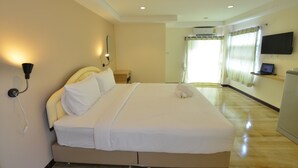 Habitación de hotel con una cama grande, un televisor de pantalla plana en la pared y un escritorio con una computadora.