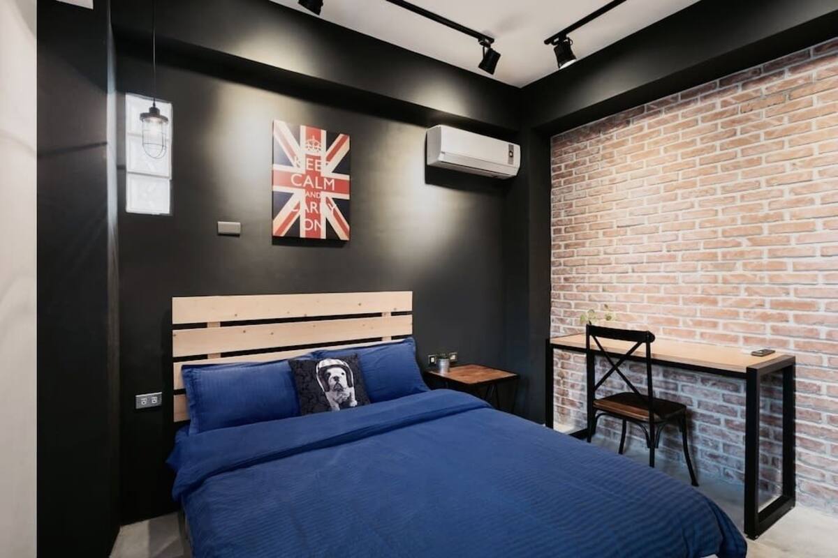 A modern bedroom with a wooden bed, blue bedding, a small table, and a chair.