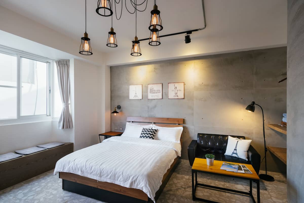 A modern bedroom with a bed, bedside tables, a bench, a sofa, and a coffee table.