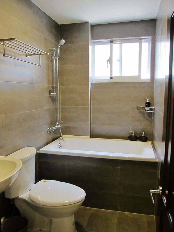 Un baño con bañera, inodoro y ventana.