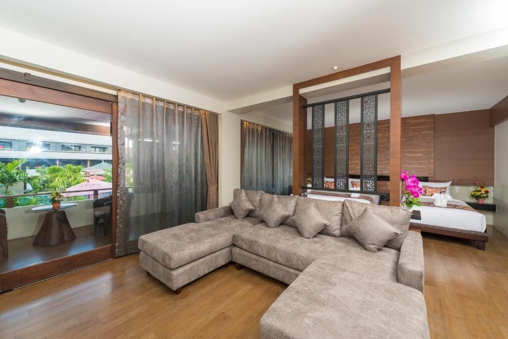 A modern living room with a sectional sofa, a bed, and a large sliding glass door leading to an outdoor area.