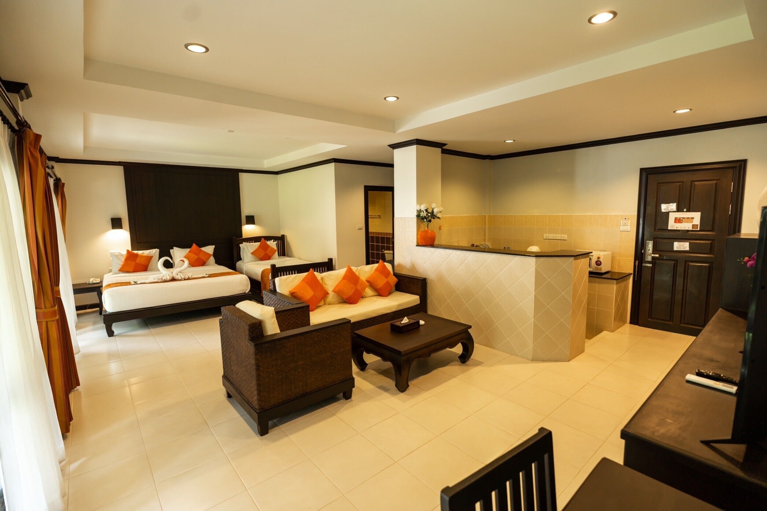 A hotel room with a bed, a sofa, a coffee table, and a kitchenette area.