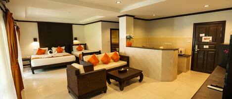A hotel room with a bed, a sofa, a coffee table, and a kitchenette area.