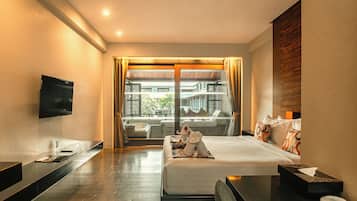 A hotel room with a bed, a TV, a desk, and a view of the outside.