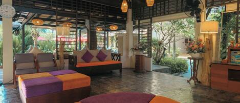 A spacious lobby with a sofa set, a wooden bench, and a dining area.