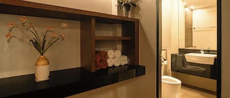 Un baño con encimera negra, un florero con flores y toallas dobladas con esmero.