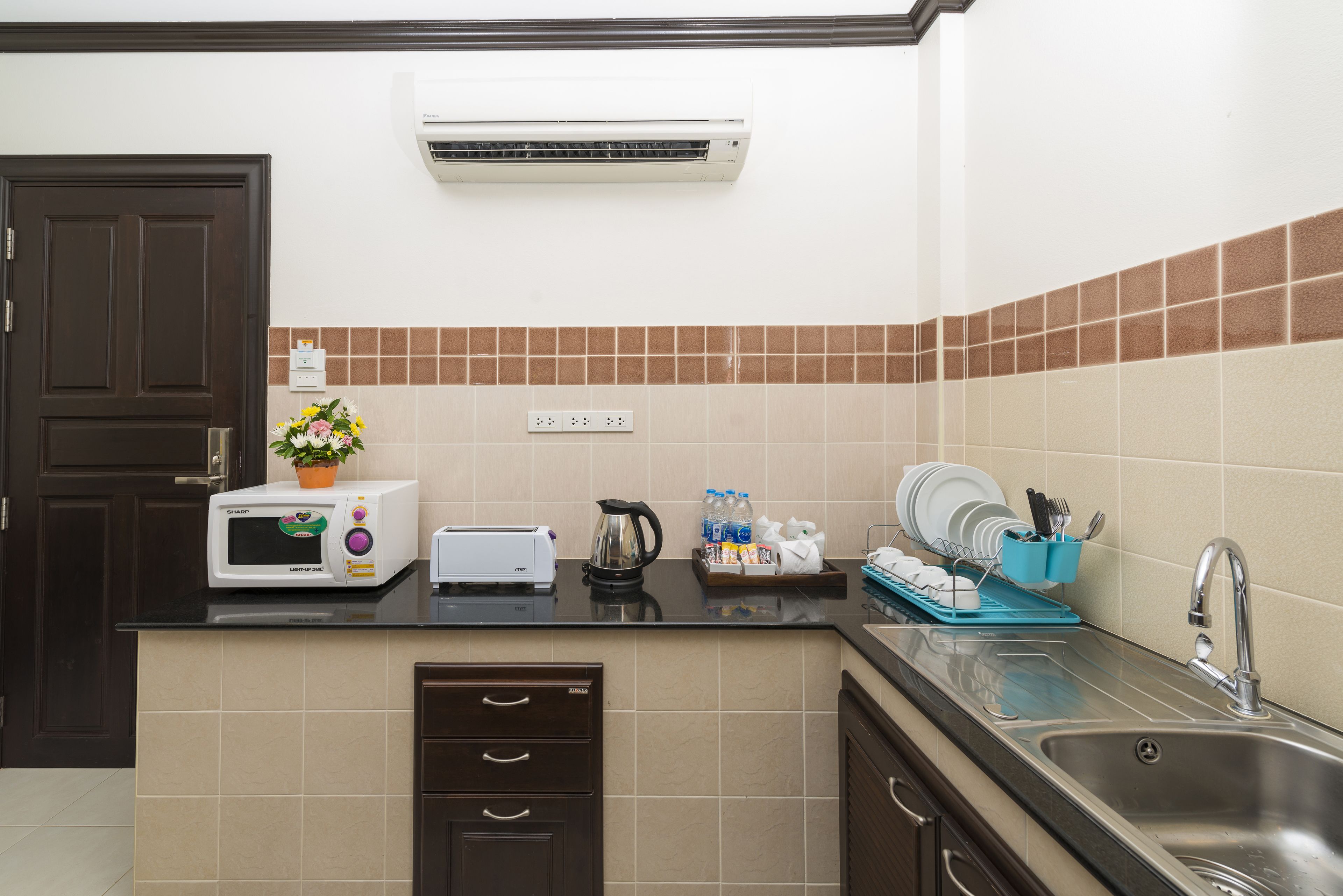 A kitchen with a microwave, toaster, sink, and a potted plant.