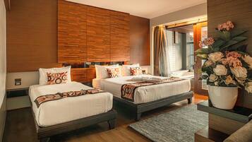 Ein modernes Hotelzimmer mit zwei Betten, Holzwandverkleidung, einem großen Spiegel und einer Blumenvase.