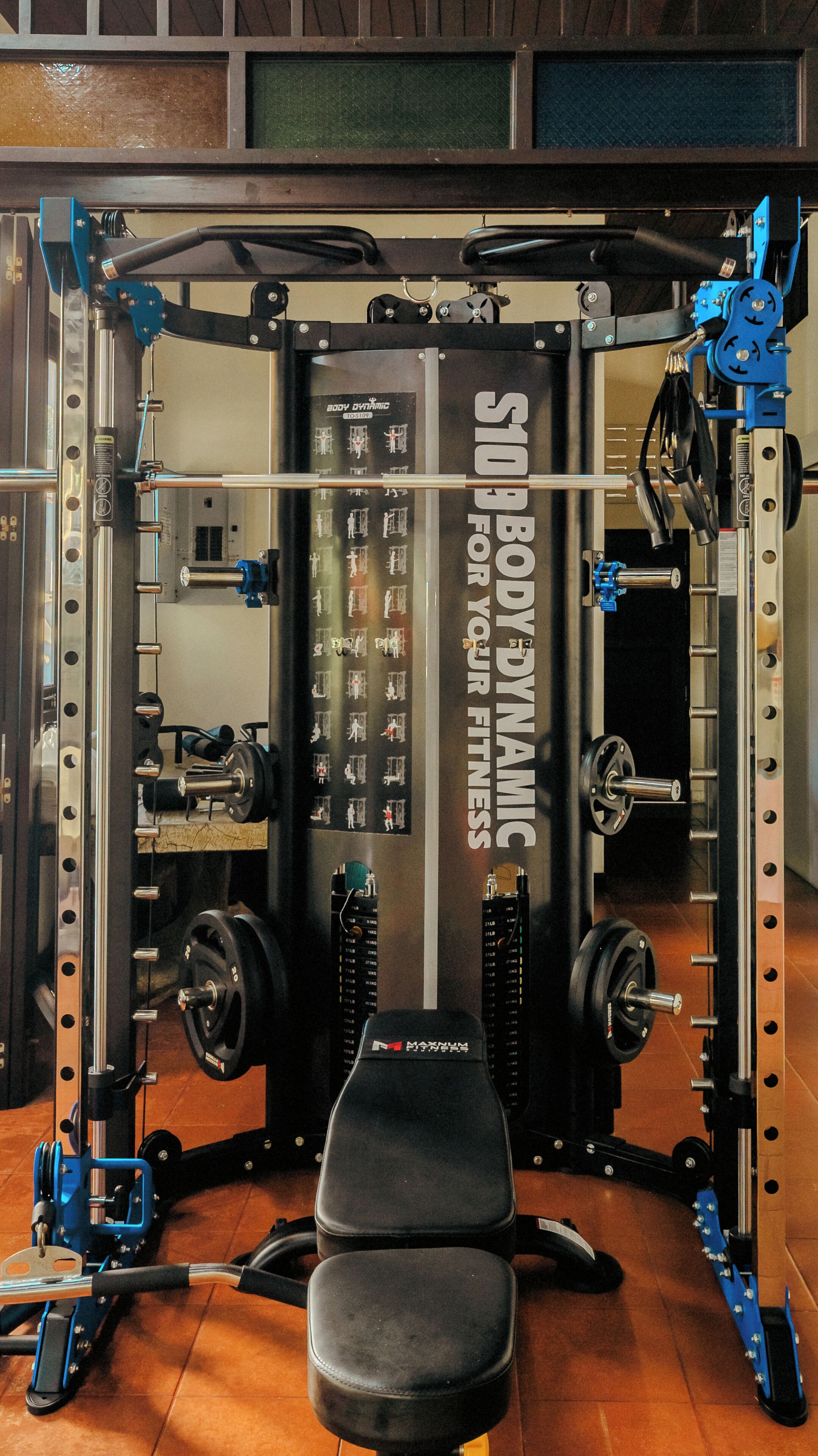 A gym with a squat rack, bench, and weight plates.