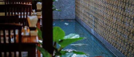 A narrow indoor water feature with a tiled wall and a wooden table with chairs.