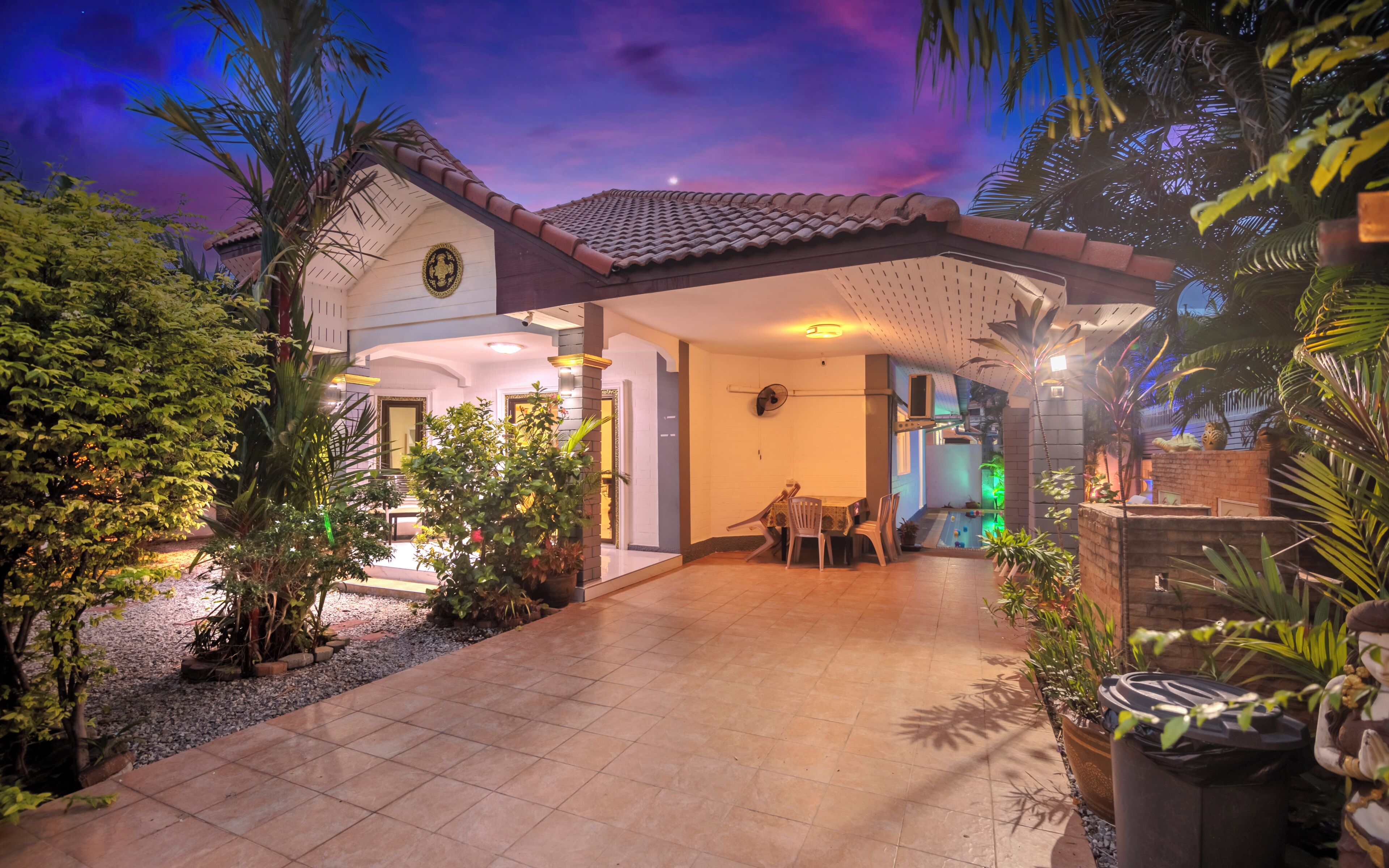 A house with a tiled patio, a dining area, and a pool.