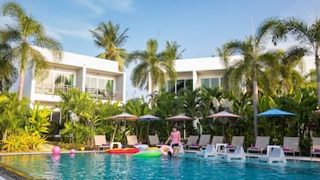 Una piscina al aire libre, sombrillas, sillones reclinables de piscina