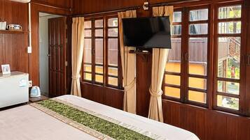 A hotel room with a large bed, wooden walls, a television, and a view of the outdoors.
