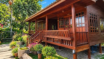 Una casa de madera con porche, plantas en macetas y un camino de piedra.
