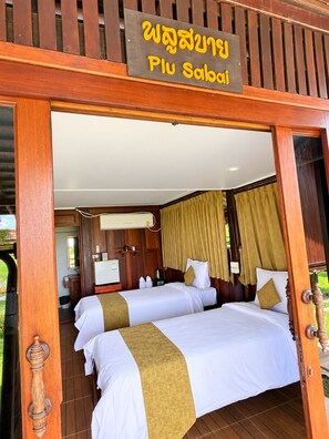 A hotel room with two beds, a wooden door frame, and a sign above the entrance.