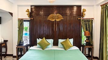 A hotel room with a large bed, a wooden headboard, a chandelier, and a view of the outdoors.