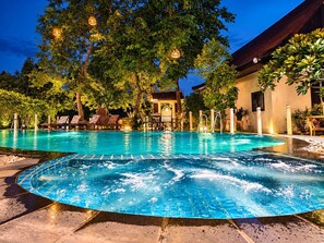 A swimming pool with lounge chairs and a building in the background. - Pludhaya Resort & Spa (Ayutthaya)